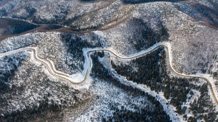 Aerial view of the river and taiga forests and road in the winter - springtime . Abstract landscape of northern nature with drone.の写真素材