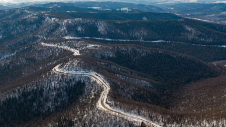 Aerial view of the river and taiga forests and road in the winter - springtime . Abstract landscape of northern nature with drone.の写真素材