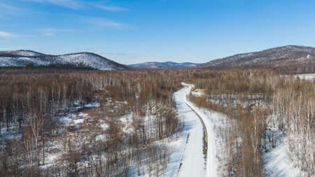 Aerial view of the river and taiga forests and road in the winter - springtime . Abstract landscape of northern nature with drone.の写真素材