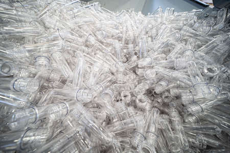 The various type of plastic bottle product and preform material with injection mold background. Drinking container manufacturing processing.の写真素材