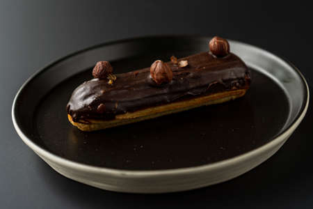 dessert is a small puff pastry pie with stuffing inside on a black serving plate on a black background . A piece of cake with a cutの写真素材