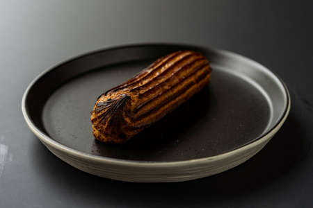 dessert is a small puff pastry pie with stuffing inside on a black serving plate on a black...