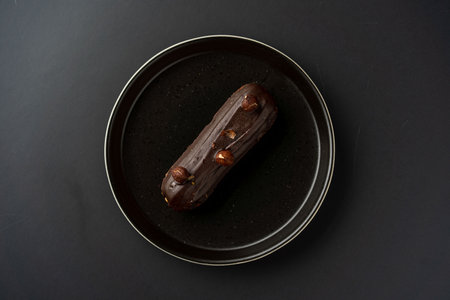 dessert is a small puff pastry pie with stuffing inside on a black serving plate on a black...