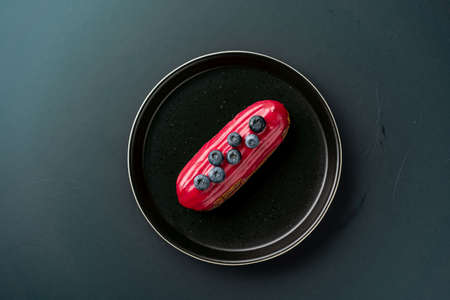 dessert is a small puff pastry pie with stuffing inside on a black serving plate on a black background . A piece of cake with a cutの写真素材