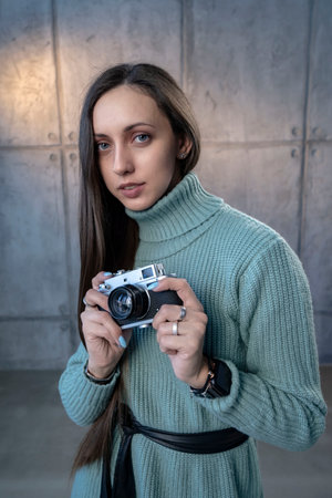 beautiful girl with an old camera in her hands in a green dress. looking at the camera smiling