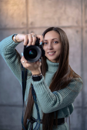 beautiful girl with a modern camera in her hands in a green dress. looking at the camera smiling