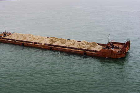 A large barge with soil floats into the sea top view