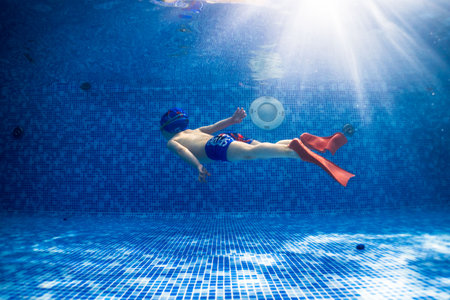 Little child swims underwater in swimming pool, happy active dives and has fun under water, kid fitness and sportの写真素材