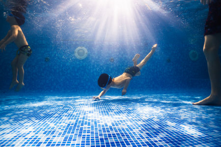 Little child swims underwater in swimming pool, happy active dives and has fun under water, kid fitness and sportの写真素材