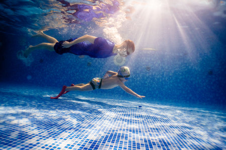 Little child swims underwater in swimming pool, happy active dives and has fun under water, kid fitness and sportの写真素材
