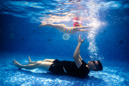 Little child swims underwater in swimming pool, happy active dives and has fun under water, kid fitness and sportの写真素材
