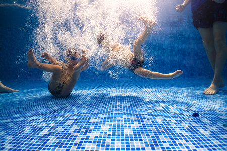 Little child swims underwater in swimming pool, happy active dives and has fun under water, kid fitness and sportの写真素材