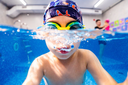 Little child swims underwater in swimming pool, happy active dives and has fun under water, kid fitness and sportの写真素材