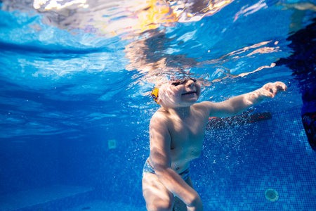 Little child swims underwater in swimming pool, happy active dives and has fun under water, kid fitness and sportの写真素材