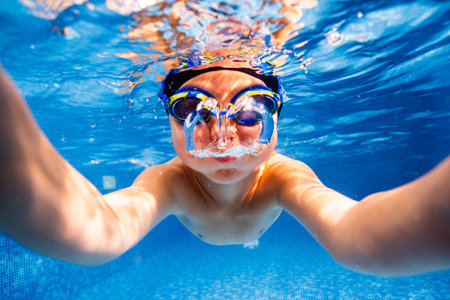 Little child swims underwater in swimming pool, happy active dives and has fun under water, kid fitness and sportの写真素材