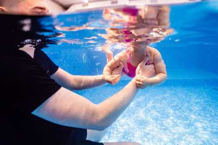 Little child swims underwater in swimming pool, happy active dives and has fun under water, kid fitness and sportの写真素材
