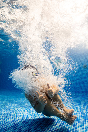 Little child swims underwater in swimming pool, happy active dives and has fun under water, kid fitness and sportの写真素材