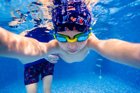 Little child swims underwater in swimming pool, happy active dives and has fun under water, kid fitness and sportの写真素材