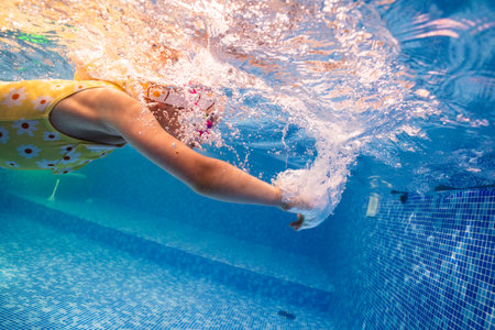 Little child swims underwater in swimming pool, happy active dives and has fun under water, kid fitness and sportの写真素材