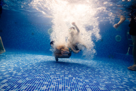 Little child swims underwater in swimming pool, happy active dives and has fun under water, kid fitness and sportの写真素材