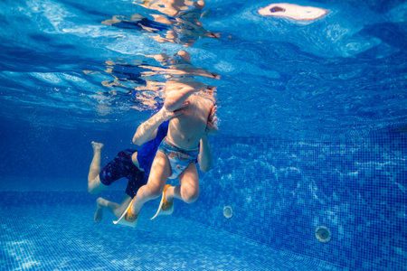 Little child swims underwater in swimming pool, happy active dives and has fun under water, kid fitness and sportの写真素材