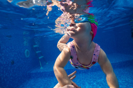Little child swims underwater in swimming pool, happy active dives and has fun under water, kid fitness and sportの写真素材