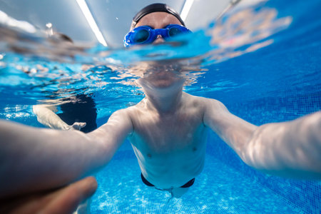 Little child swims underwater in swimming pool, happy active dives and has fun under water, kid fitness and sportの写真素材