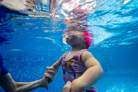 Little child swims underwater in swimming pool, happy active dives and has fun under water, kid fitness and sportの写真素材