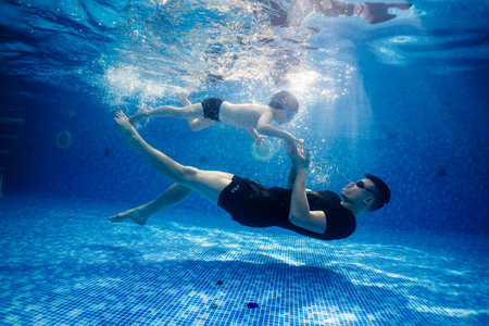 Little child swims underwater in swimming pool, happy active dives and has fun under water, kid fitness and sportの写真素材