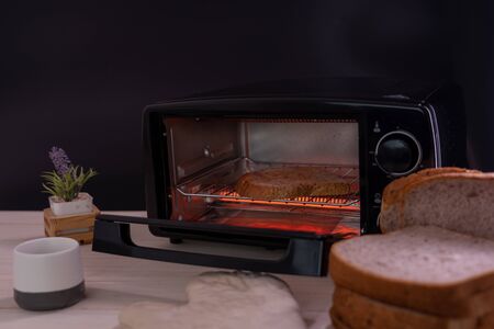 Black micro electric oven with whole wheat bread.の写真素材