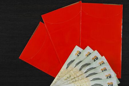 red envelope with money on black wood backgroundの写真素材