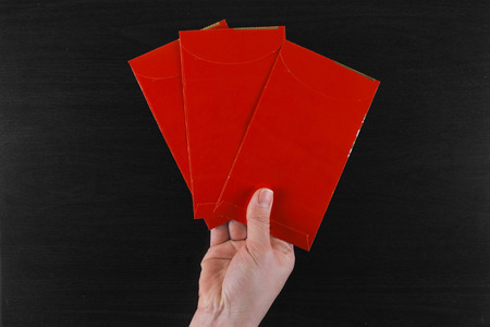 red envelope carried by hand on black wood backgroundの写真素材