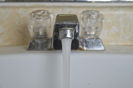 dirty white sink with water runningの写真素材