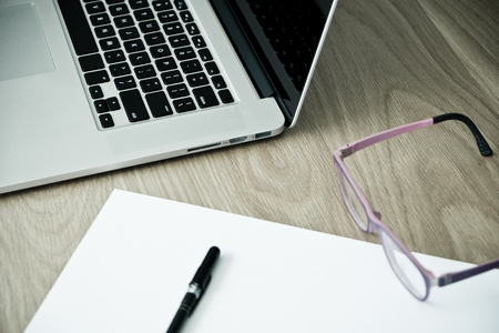 paper, pen, glasses, and laptop on wood table backgroundの写真素材