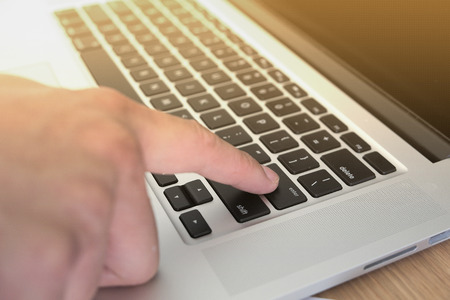 closeup finger press on enter button with light from left corner background