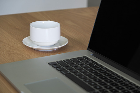 a cup of coffee with laptop on desk backgroundの写真素材