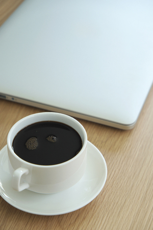 a cup of coffee with laptop on desk background in top viewの写真素材