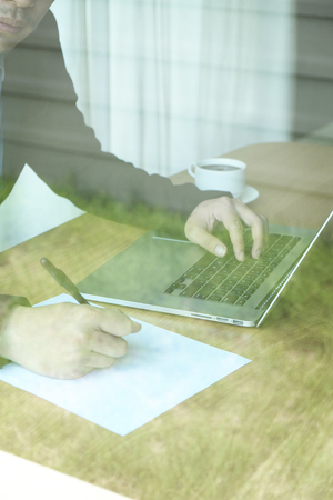 a business man with pen, paper, and laptopの写真素材