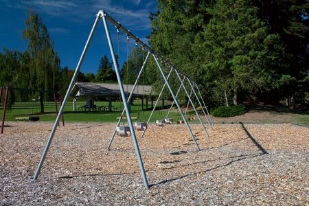 A large toddler swing set in a beautiful park over bark mulch for safety.