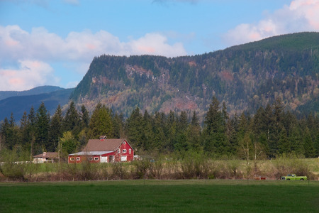 A red barn, hay field and Mount Enumclaw present an idyllic spring landscape in Washington State.のeditorial素材