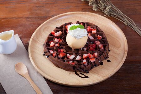 Chocolate waffle with strawberry and ice-cream vanilla on top has whip cream and peppermint.の写真素材