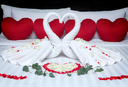 Fold a towel swan for decorations with rose petals on wedding bed.の写真素材