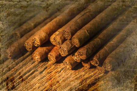 Pile of small cigar on old wooden table overlap with old wall textured background. retro filter.の写真素材