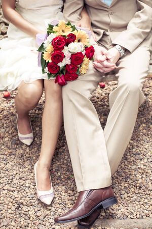 close up bokeh on hands of Bride and groom and sitting on the benchの写真素材