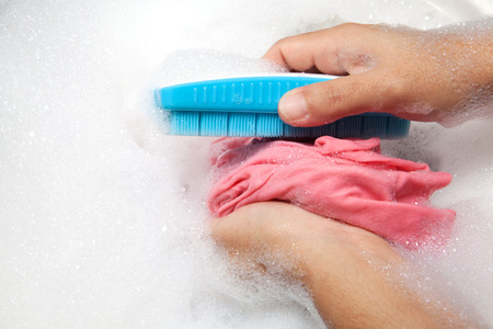 Hand washing clothes with bubble on white basin.の写真素材