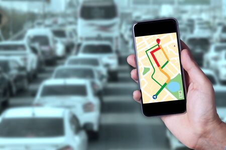 Hand of man using map on smartphone application with traffic jam background.