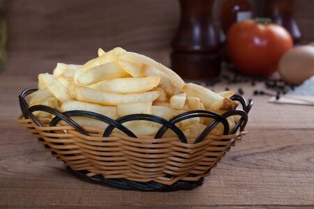 French fries in basket on the wood table.