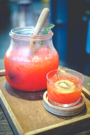 Punch juice and kiwi in glass and jar.
