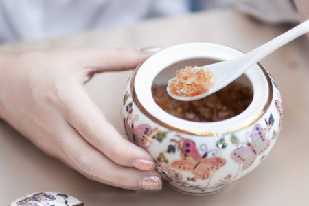 Natural rock sugar in Thai bowl (thai benjarong) and women hands.の写真素材