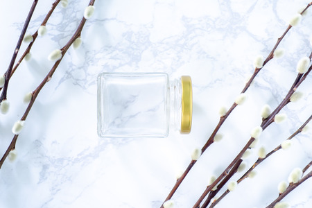 Square glass jars gold lid packaging on marble table and cotton flower.